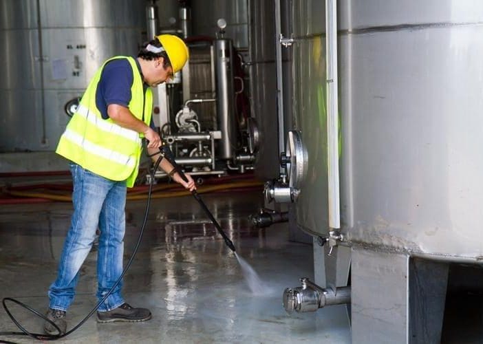 A man power-washing a floor