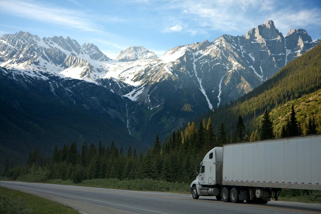 A large white truck driving towards the mountains