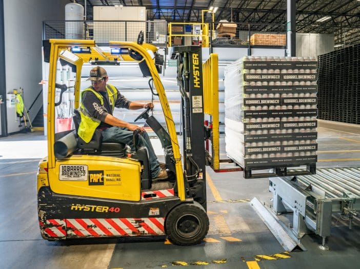 What is the process for shipping heavy machinery abroad? A forklift truck is moving pallets in a warehouse.